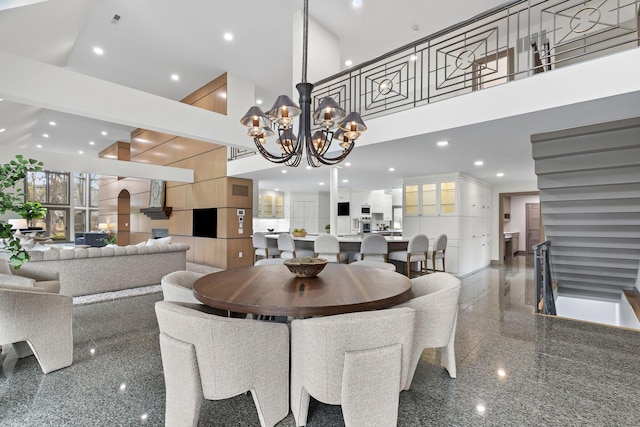 dining room with granite finish floor, recessed lighting, an inviting chandelier, and a towering ceiling