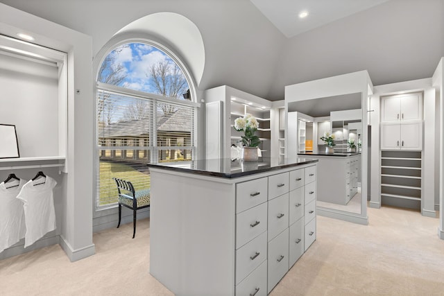 spacious closet with light colored carpet and high vaulted ceiling