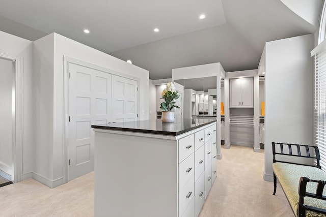 kitchen featuring dark countertops, a center island, recessed lighting, and light carpet