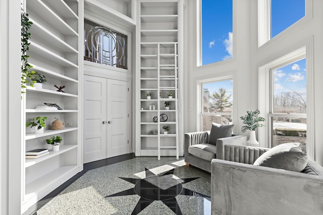 living area with granite finish floor, built in features, and a high ceiling