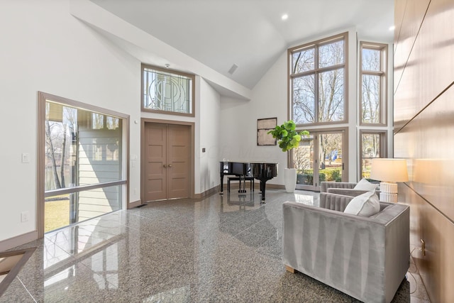 living room with plenty of natural light, granite finish floor, baseboards, and high vaulted ceiling