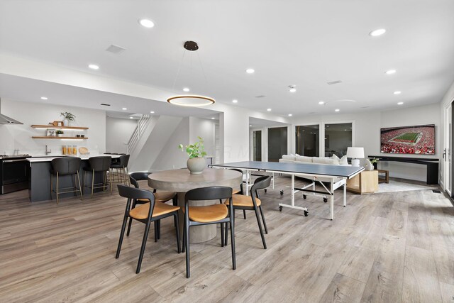 dining room featuring light wood finished floors, recessed lighting, and a community bar