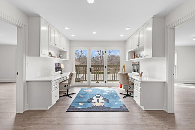 office with built in desk, recessed lighting, and wood finished floors