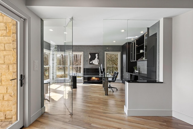 interior space with open shelves, dark countertops, light wood-style floors, and a warm lit fireplace