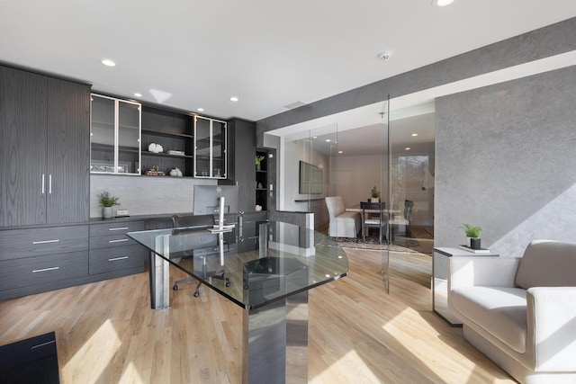 kitchen with modern cabinets, tasteful backsplash, recessed lighting, light wood finished floors, and glass insert cabinets