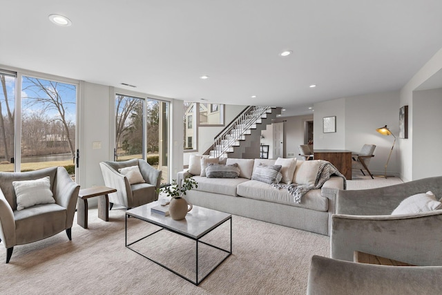 living area with recessed lighting, stairway, light colored carpet, and floor to ceiling windows