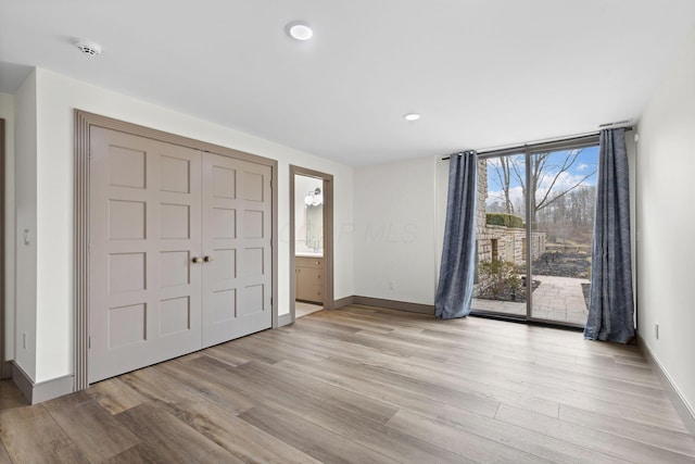 foyer entrance featuring a wall of windows, recessed lighting, baseboards, and light wood finished floors