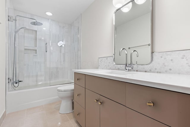 bathroom featuring tile patterned flooring, toilet, decorative backsplash, combined bath / shower with glass door, and vanity