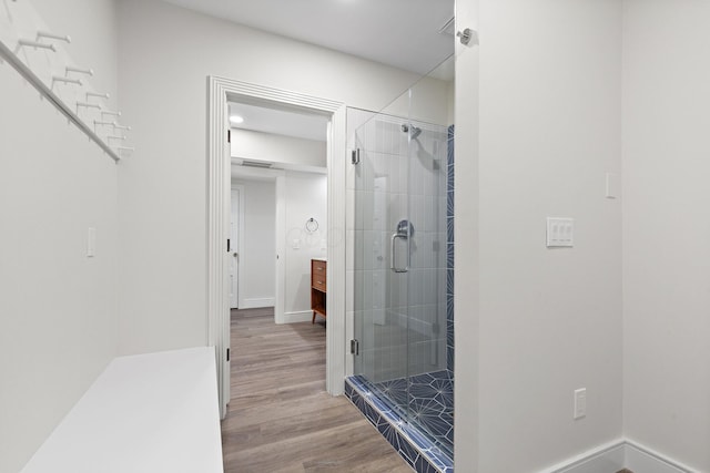 bathroom featuring a stall shower, baseboards, and wood finished floors