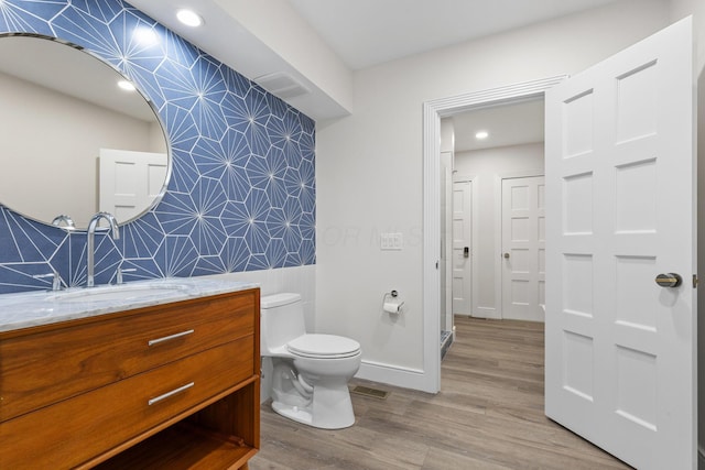 full bath with wallpapered walls, baseboards, toilet, wood finished floors, and vanity