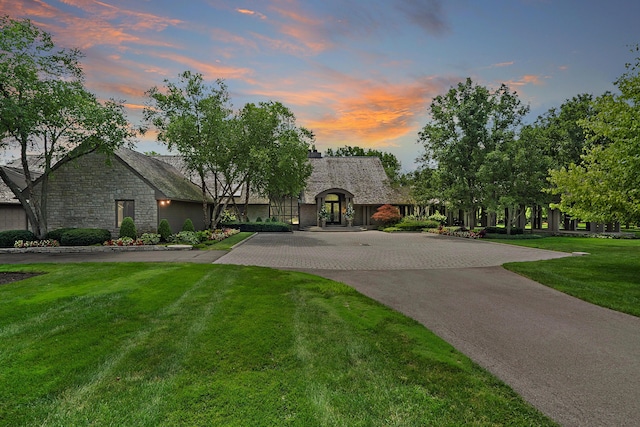 french country home with stone siding, driveway, and a front yard