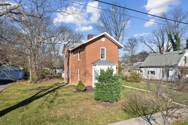 view of side of home featuring a yard, brick siding, and a chimney