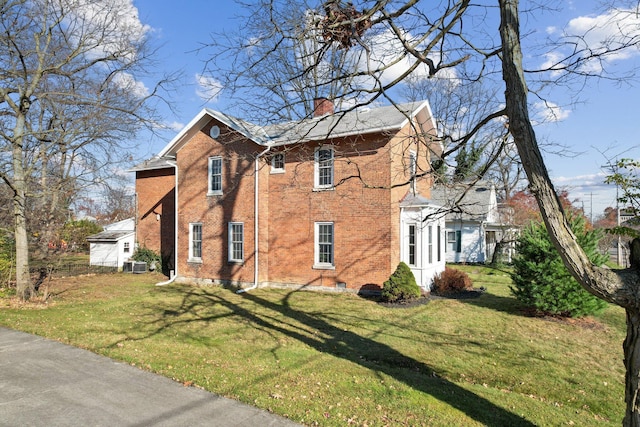 view of side of home with a lawn, brick siding, central AC, and a chimney