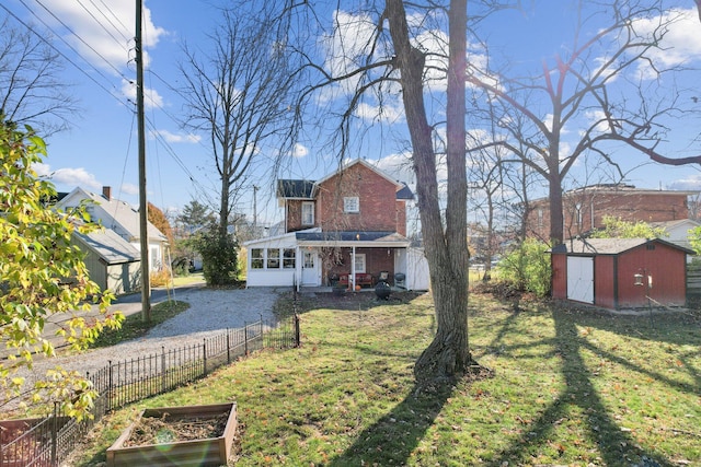 view of front of house featuring brick siding, a vegetable garden, a front lawn, and a shed