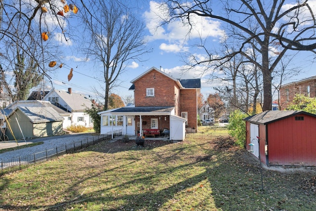 back of property featuring brick siding, fence, a storage shed, an outdoor structure, and a yard