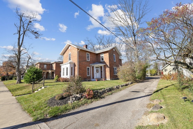 view of front of house with a front yard, brick siding, and a chimney