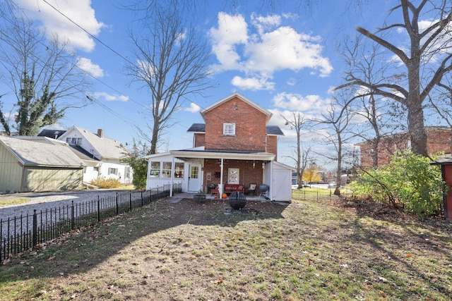 back of property featuring brick siding, a porch, and a fenced backyard