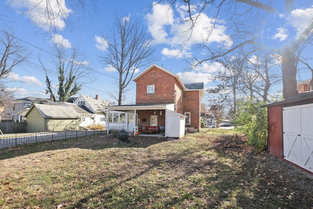 back of property featuring fence, brick siding, an outdoor structure, and a shed