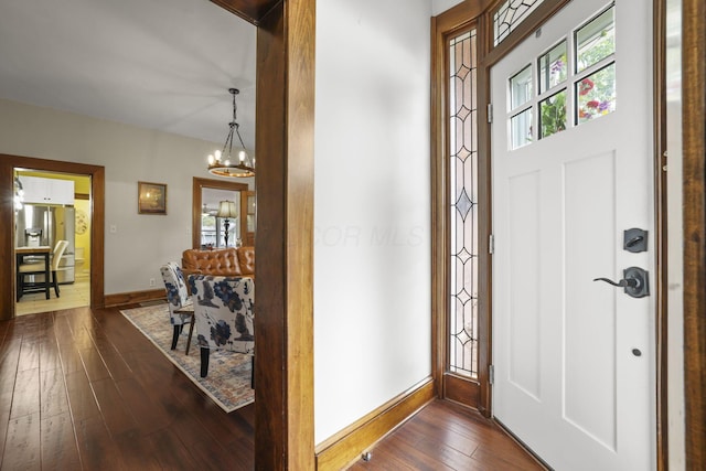 entryway featuring dark wood-style floors, baseboards, and a chandelier