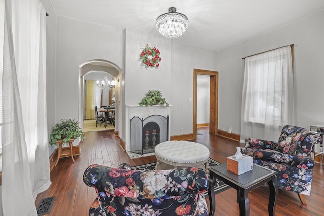 living area featuring visible vents, arched walkways, a notable chandelier, and hardwood / wood-style flooring