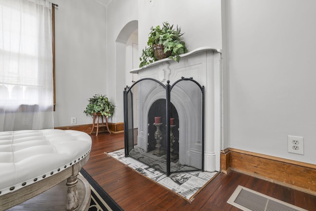 details with arched walkways, visible vents, a fireplace with flush hearth, and wood finished floors