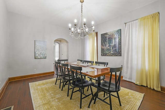 dining space featuring baseboards, arched walkways, visible vents, and wood-type flooring