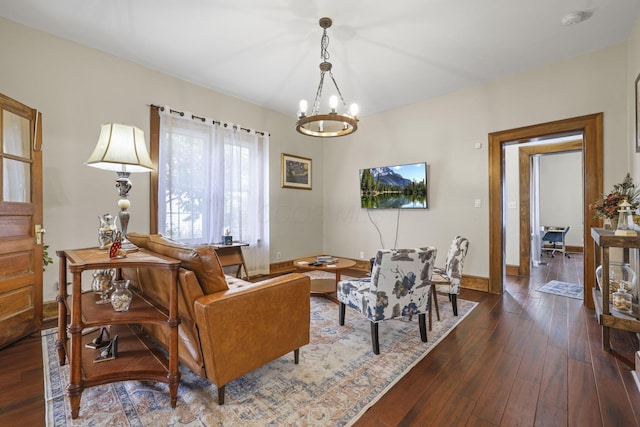 living room with dark wood-type flooring, a notable chandelier, and baseboards