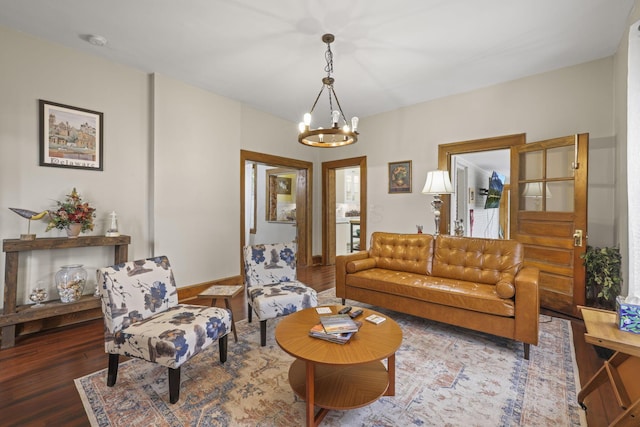 living area with baseboards, an inviting chandelier, and wood finished floors