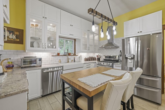 kitchen with a sink, stainless steel appliances, light wood-type flooring, and backsplash