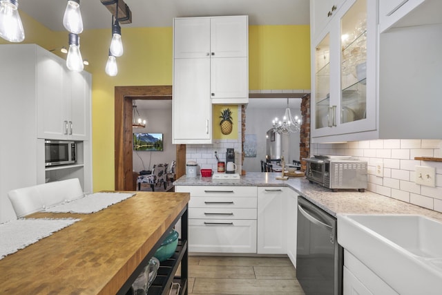 kitchen with decorative backsplash, appliances with stainless steel finishes, white cabinetry, and wood counters