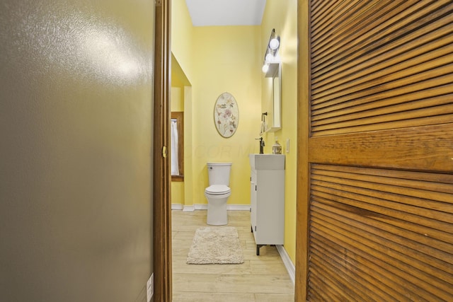 bathroom with vanity, toilet, wood finished floors, and baseboards