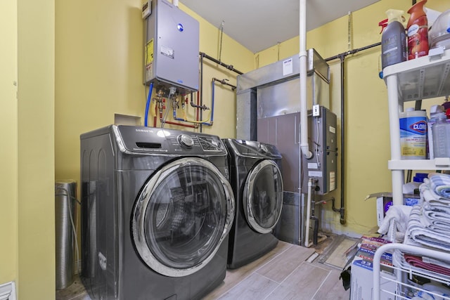 laundry room featuring tankless water heater, laundry area, washer and dryer, and wood finish floors