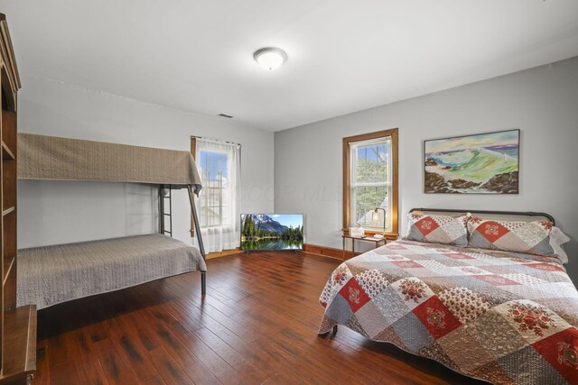 bedroom with visible vents, multiple windows, baseboards, and hardwood / wood-style flooring