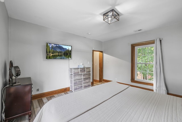 bedroom with visible vents, baseboards, and wood finished floors