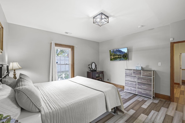 bedroom featuring visible vents, baseboards, and wood finished floors