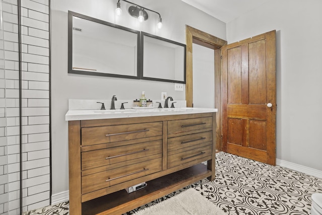 full bathroom with double vanity, tile patterned flooring, baseboards, and a sink