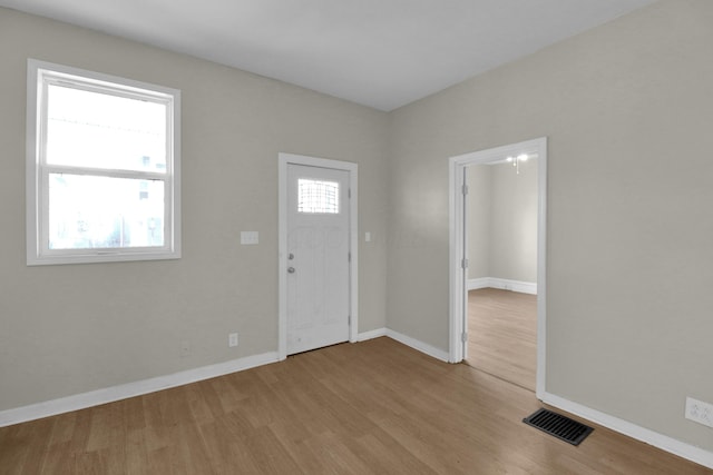 foyer featuring plenty of natural light, wood finished floors, visible vents, and baseboards