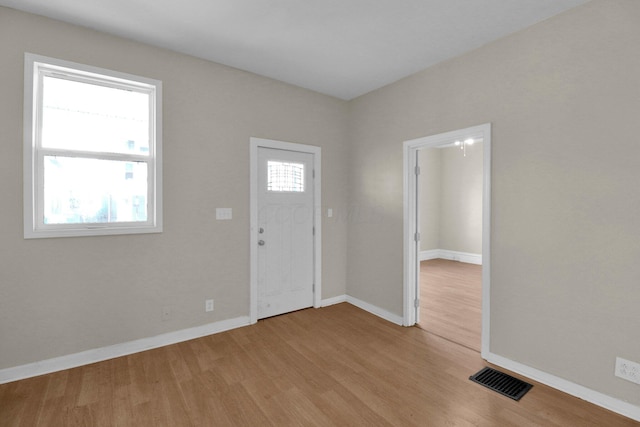 foyer with wood finished floors, visible vents, and baseboards