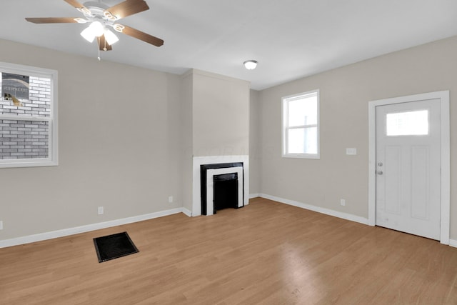 unfurnished living room featuring a fireplace, light wood-style flooring, baseboards, and ceiling fan