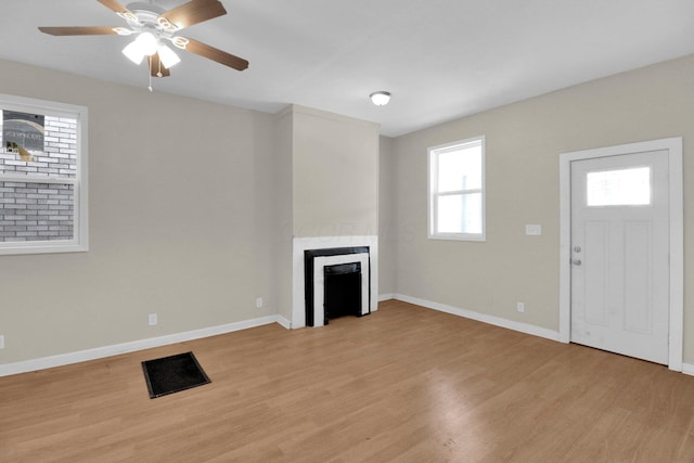 unfurnished living room featuring light wood-style floors, a fireplace, baseboards, and a ceiling fan