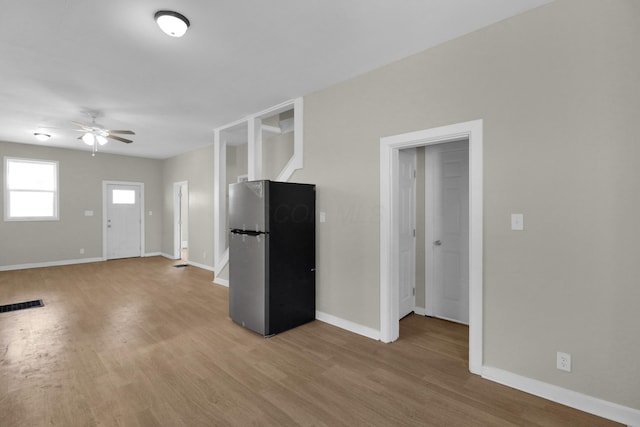 unfurnished living room with baseboards, visible vents, ceiling fan, and light wood finished floors