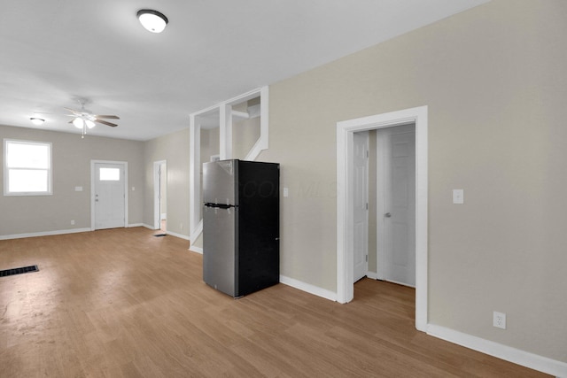 unfurnished living room with a ceiling fan, light wood-type flooring, visible vents, and baseboards