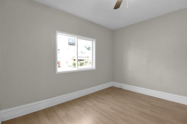 spare room featuring light wood-style floors, baseboards, and a ceiling fan