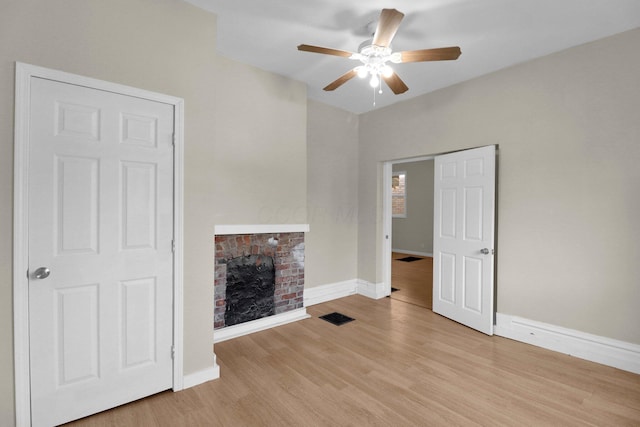 unfurnished living room with a fireplace, visible vents, light wood-style flooring, a ceiling fan, and baseboards