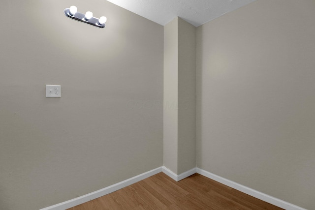 spare room with baseboards and wood finished floors