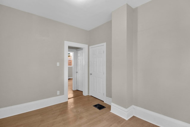 unfurnished room with wood finished floors, visible vents, and baseboards