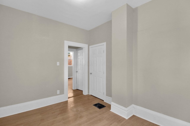 spare room with wood finished floors, visible vents, and baseboards