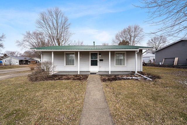 view of front of property with covered porch, metal roof, and a front lawn