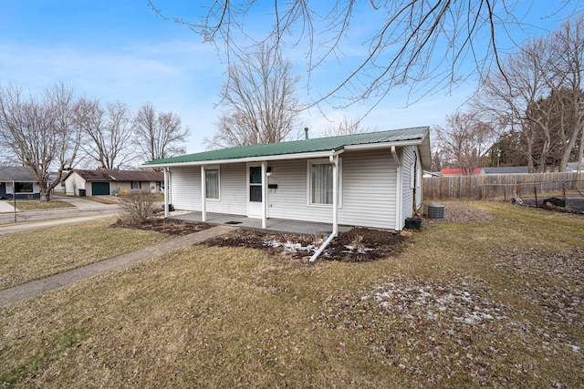 view of front facade featuring central AC unit, a porch, metal roof, fence, and a front lawn