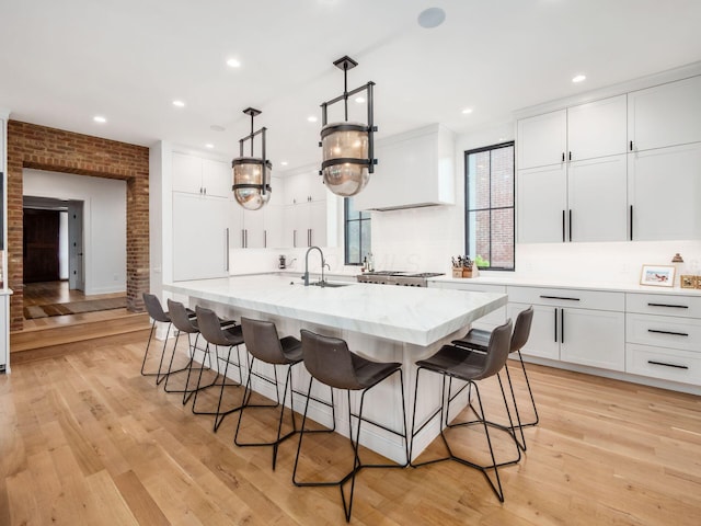 597 S 9th St, Columbus, OH 43206 - kitchen with a sink, white cabinetry, a kitchen breakfast bar, light wood-style flooring, and recessed lighting